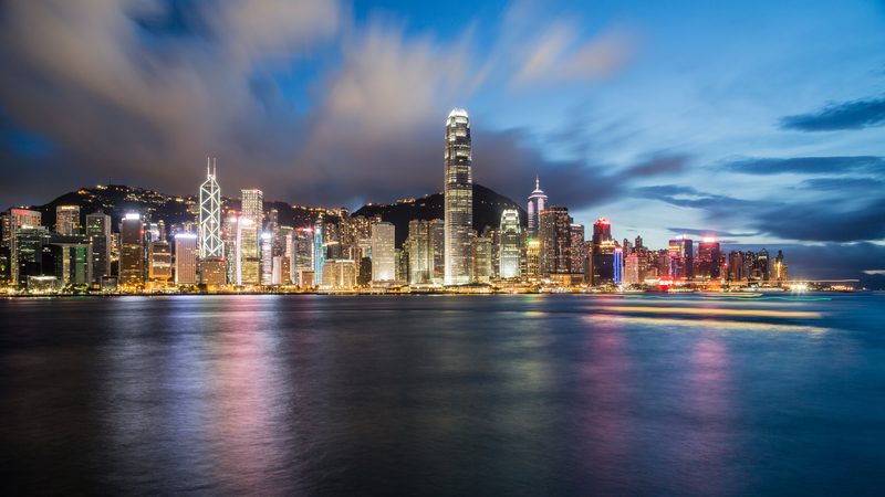 Night skyline of a harbour city, towers lit along the waterfront.