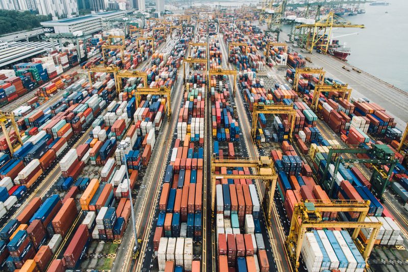 Aerial view of a container port with rows of stacked containers and gantry cranes.