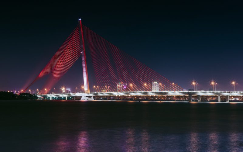A cable-stayed bridge lit red at night.